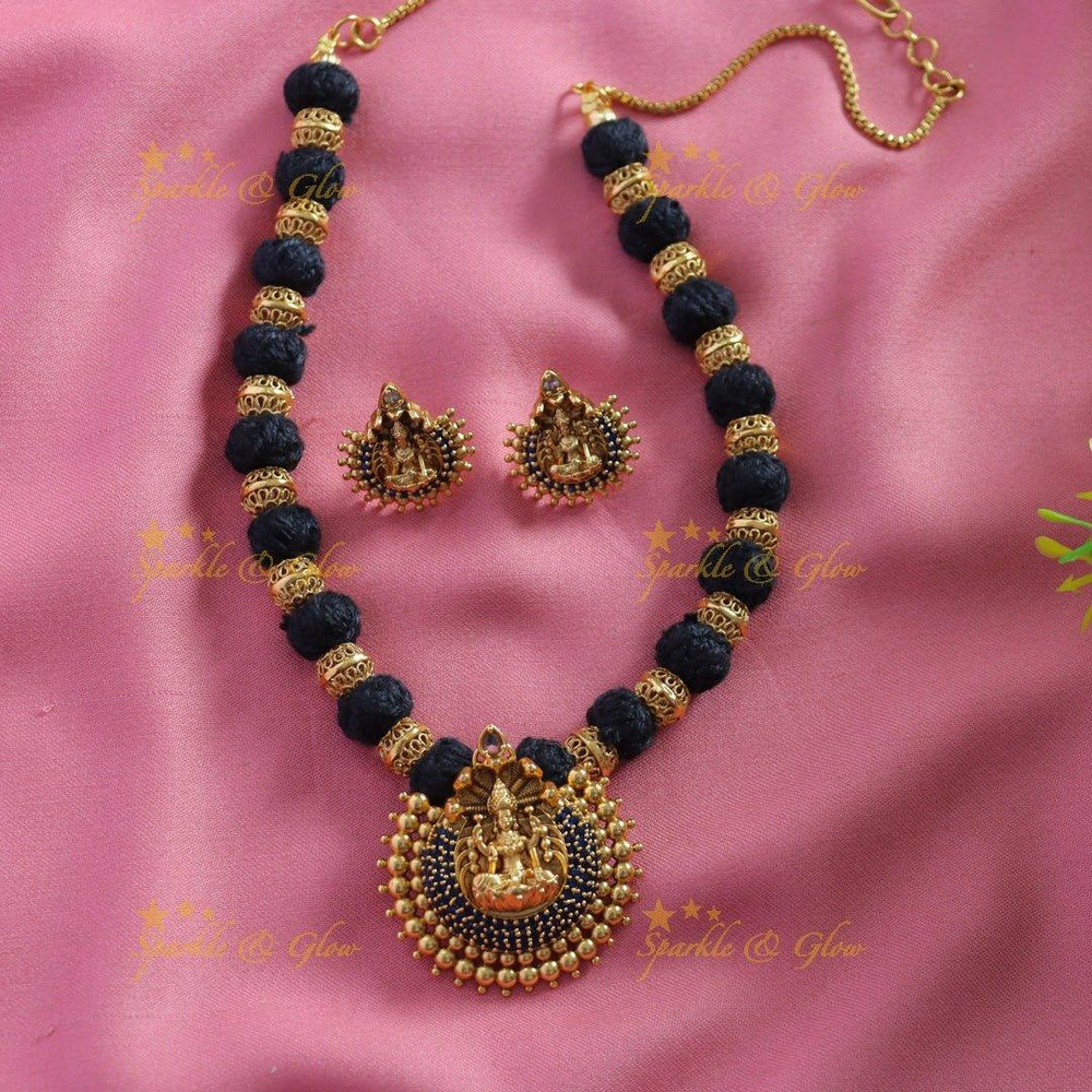 Statement Lakshmi carved pendant black thread short necklace with gold beads and blue stones - Sparkle and Glow