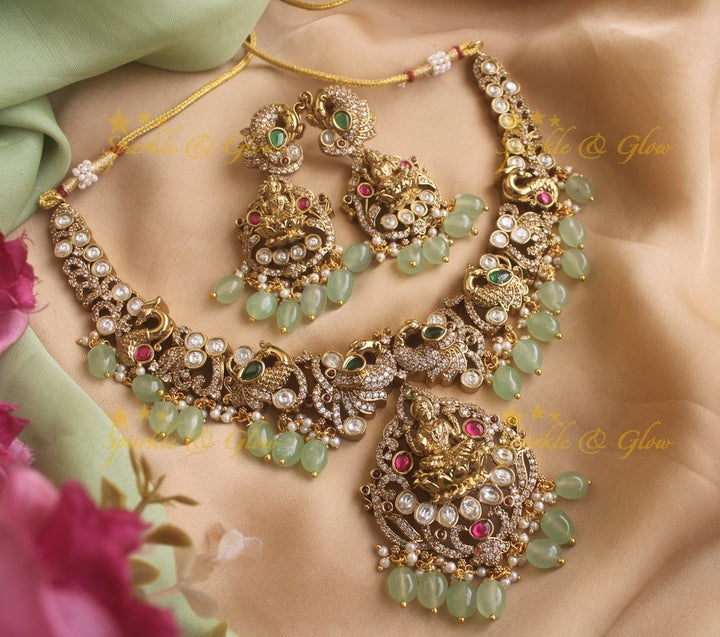 Exquisite Lakshmi and Peacock Victorian Gold finish AD necklace with ruby emerald pastel green beads