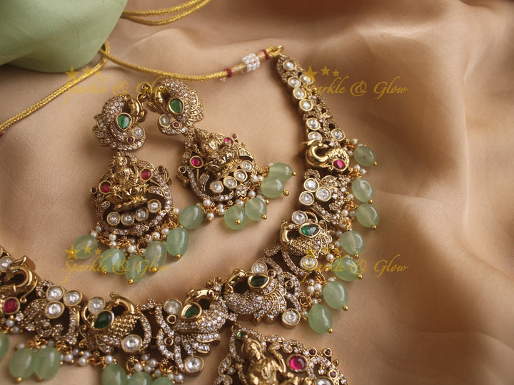 Exquisite Lakshmi and Peacock Victorian Gold finish AD necklace with ruby emerald pastel green beads