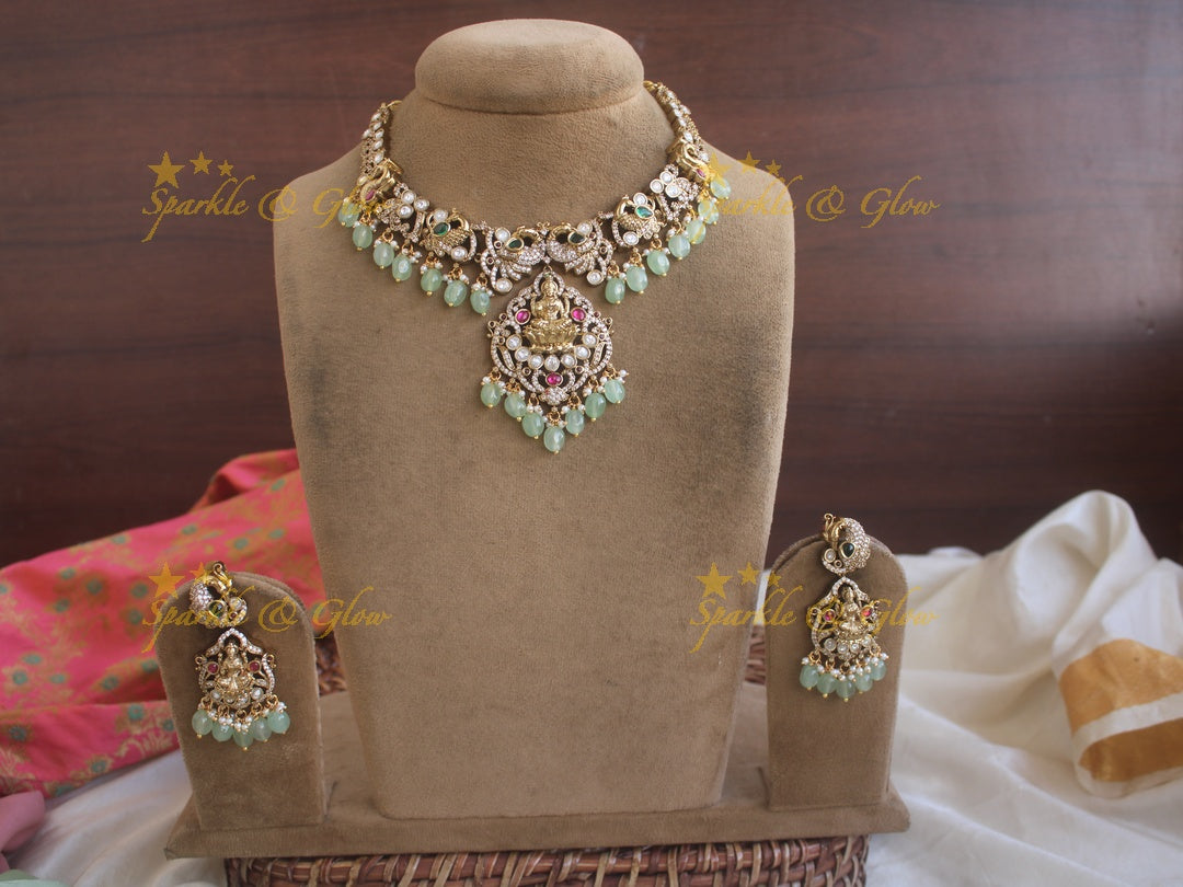 Exquisite Lakshmi and Peacock Victorian Gold finish AD necklace with ruby emerald pastel green beads